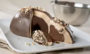 Un delizioso tartufo alla nocciola, con strati di gelato al cioccolato e crema, ricoperto di cioccolato e granella di nocciole.