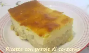 Una fetta di torta di riso carrarina, con una base soffice e una crema dorata in superficie, servita su un piatto a scacchi.
