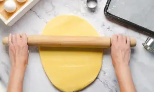 Mani stendono la pasta frolla senza burro con un mattarello. Ingredienti per dolci leggeri.
