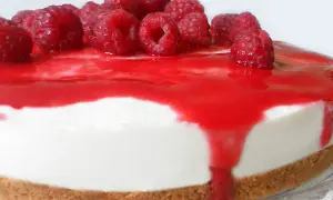 Cheesecake ai lamponi con coulis rosso e lamponi freschi, una delizia per gli occhi e per il palato.