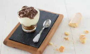Delizioso bicchiere con crema al mascarpone e cacao, guarnito con una colata di cioccolato fondente.
