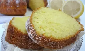 Fette di torta al limone spolverate di zucchero a velo, con fette di limone sullo sfondo.