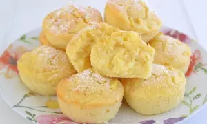 Muffin alle mele soffici e dorati, cosparsi di zucchero a velo, su un piatto fiorito. Uno è tagliato a metà, mostrando la morbida consistenza.