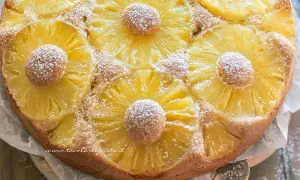 Torta ananas dorata e profumata, decorata con fette di ananas caramellato e spolverata di zucchero a velo.