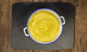 Una ciotola di cremosa crema pasticcera vegana, con un vortice lucido al centro, pronta per farcire dolci.