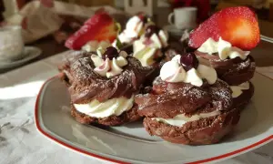 Zeppole al cacao con panna montata, ciliegie e fragole, spolverate di zucchero a velo.