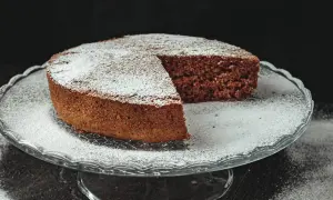 Torta al cioccolato soffice, una delizia senza farina e lievito, cosparsa di zucchero a velo su un'alzata di vetro.
