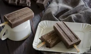Tre ghiaccioli al cioccolato, uno su una tazza bianca, gli altri su un piatto, con pezzi di cioccolato sullo sfondo.