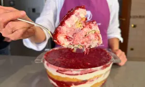 Un cucchiaio solleva una porzione generosa di tiramisù alle fragole, mostrando strati cremosi e succosi.