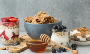 Colazione sana con cereali, yogurt, fragole e mirtilli. Un tocco di miele per dolcificare.