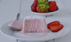 Delizioso semifreddo alle fragole, con una porzione su un cucchiaio e fragole fresche sullo sfondo.