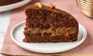 Una fetta di torta al cioccolato con ripieno di caramello e noci, perfetta tra i dolci per le feste.