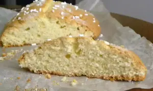 Fetta di ciambella romagnola soffice e dorata, cosparsa di zuccherini, su carta da forno.
