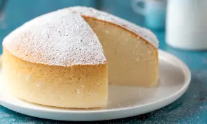 Una soffice torta nuvola, cosparsa di zucchero a velo, attende di essere gustata su un piatto bianco.