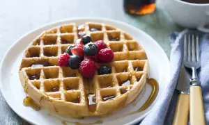 Waffle dorato con sciroppo d'acero e frutti di bosco, perfetto per una ricetta waffle golosa.