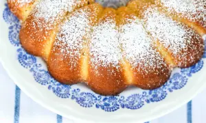 Deliziosa torta al latte caldo, cosparsa di zucchero a velo, su un piatto con decori blu.