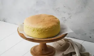 Torta soffice e dorata, preparata con albumi montati a neve, su un alzata di legno.