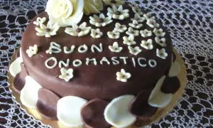 Torta al cioccolato con decorazioni in pasta di zucchero, un augurio speciale: "Buon Onomastico" per un uomo.