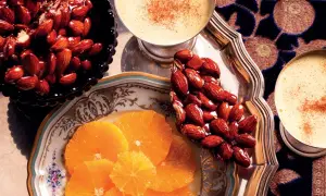 Un delizioso croccante di mandorle caramellate, accompagnato da fette d'arancia e bevande speziate.