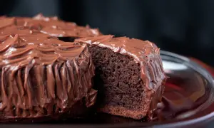 Una fetta di torta al cioccolato, soffice e umida, ricoperta da una glassa al cioccolato lucida e cremosa.