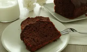 Fette di plumcake yogurt e cioccolato su un piatto, con una forchetta e un bicchiere di latte.