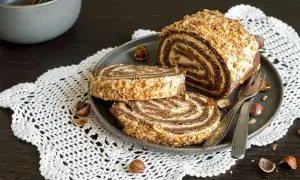 Un delizioso rotolo alla Nutella, ricoperto di granella di nocciole, pronto per essere gustato.