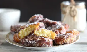 Frittelle di riso ricetta della nonna, dorate e zuccherate, su un piatto. Un assaggio di tradizione.