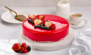 Torta rossa con glassa a specchio, decorata con fragole, mirtilli e lamponi. Un'opera d'arte culinaria.