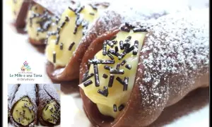 Cannoli siciliani con golosa crema al cioccolato, spolverati di zucchero a velo e granella scura. Un dolce irresistibile!