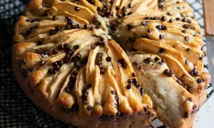 Delizioso dolce mele e cioccolato, con fette di mela disposte a raggiera e gocce di cioccolato fondente che si sciolgono nell'impasto soffice.