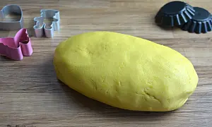 Impasto giallo per pasta frolla Bimby pronto per essere trasformato in biscotti con formine a orsetto, cuore e farfalla.
