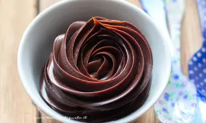 Una spirale perfetta di ganache cioccolato per copertura, lucida e invitante, in una ciotola bianca.
