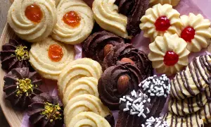 Variazioni di frolla montata: biscotti al cacao con mandorle e pistacchi, frollini con marmellata d'arancia e ciliegia, e decorati con cioccolato.