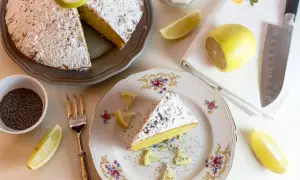 Una fetta di torta al limone leggerissima, spolverata di zucchero a velo e semi di papavero, guarnita con spicchi di limone fresco.