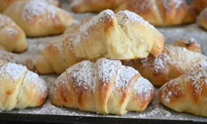 Brioches fatte in casa, dorate e soffici, cosparse di zucchero a velo. Un profumo invitante che ricorda la colazione della domenica.