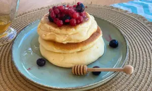 Pancake senza zucchero soffici e dorati, guarniti con frutti di bosco freschi e miele. Un dolce sano e delizioso.