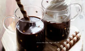 Due tazze di cioccolata calda senza fecola e senza amido, una con cialda, l'altra con panna montata e cacao.