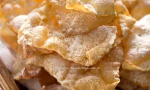 Chiacchiere croccanti, una deliziosa chiacchiere ricetta della nonna, cosparse di zucchero a velo.