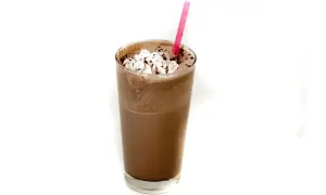 Un delizioso frappè al cioccolato, guarnito con panna montata e scaglie di cioccolato, pronto per essere gustato con una cannuccia rosa.