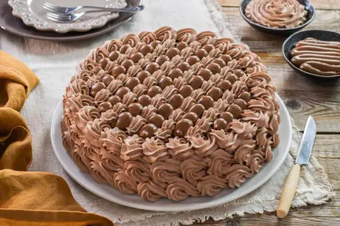 Torta decorata con abbondante crema chantilly al cioccolato e praline. Un dolce invitante pronto per essere gustato.
