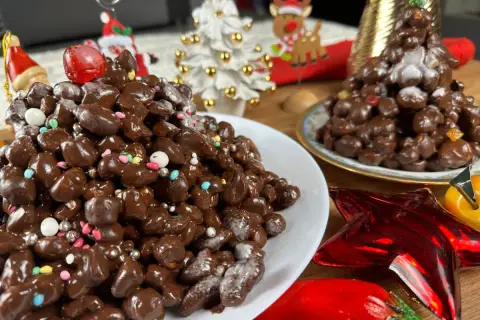 Deliziosi struffoli al cioccolato, decorati con zuccherini colorati e perline argentate, pronti per le feste natalizie.