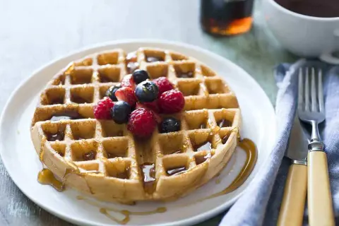 Waffle dorato con sciroppo d'acero e frutti di bosco, perfetto per una ricetta waffle golosa.
