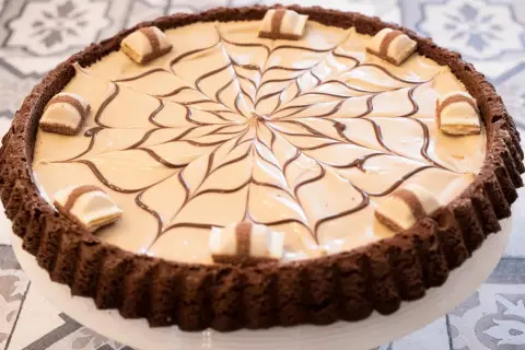 Torta Kinder Bueno con decorazione a ragnatela di cioccolato e pezzi di wafer.