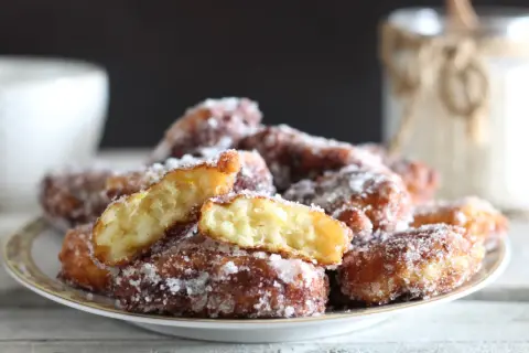 Frittelle di riso ricetta della nonna, dorate e zuccherate, su un piatto. Un assaggio di tradizione.
