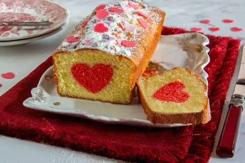 Plumcake farcito con un cuore rosso al centro, decorato con zuccherini a forma di cuore.