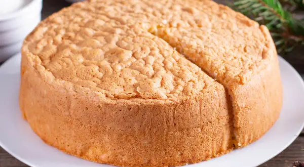 Un soffice angel cake altissima, pronto per essere decorato. La sua consistenza ariosa promette un sapore leggero e delizioso.