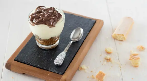 Delizioso bicchiere con crema al mascarpone e cacao, guarnito con una colata di cioccolato fondente.