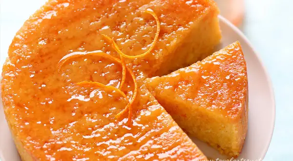 Una deliziosa torta all'arancia, lucida e profumata, con una fetta tagliata. Perfetta per una pausa golosa.