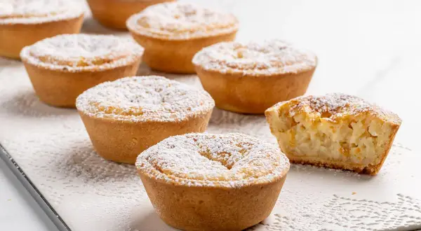 Piccoli dolci veloci, crostate con ripieno cremoso e spolverata di zucchero a velo, perfetti per una pausa golosa.