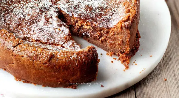 Torta soffice e golosa, uno dei tanti dolci con cioccolato al latte, spolverata di zucchero a velo su un piatto di marmo.